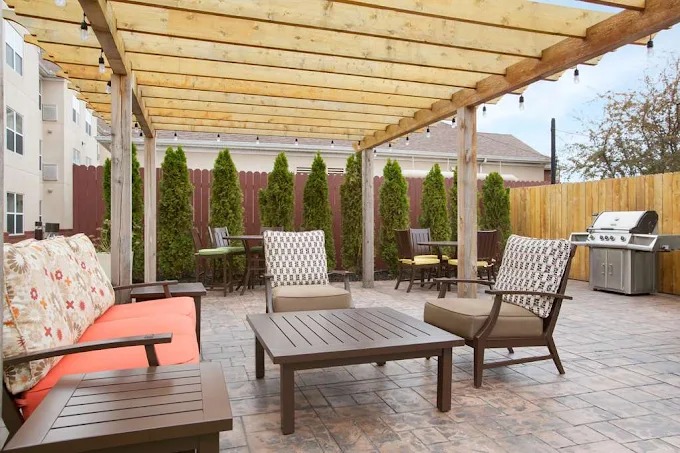 Outdoor patio area with seating and BBQ grill under pergola